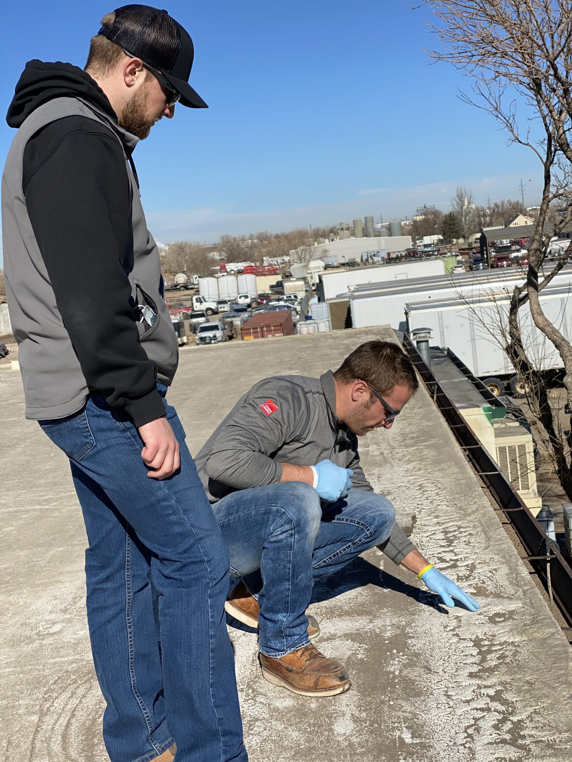 A Roof Source professional inspecing flat roof damage.