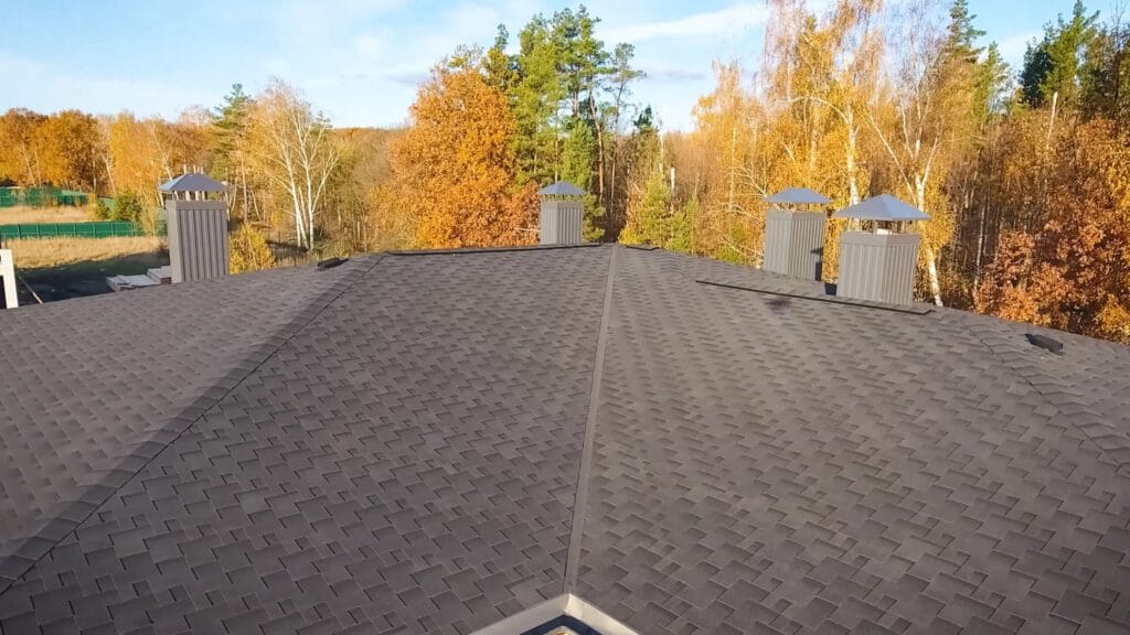 Aerial view of a completed shingle roof with vents and a skylight. 