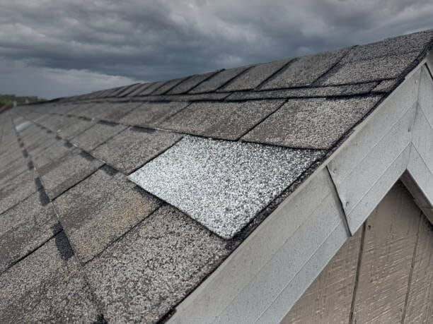 Close-up of damaged roof shingles with visible wear and granule loss.