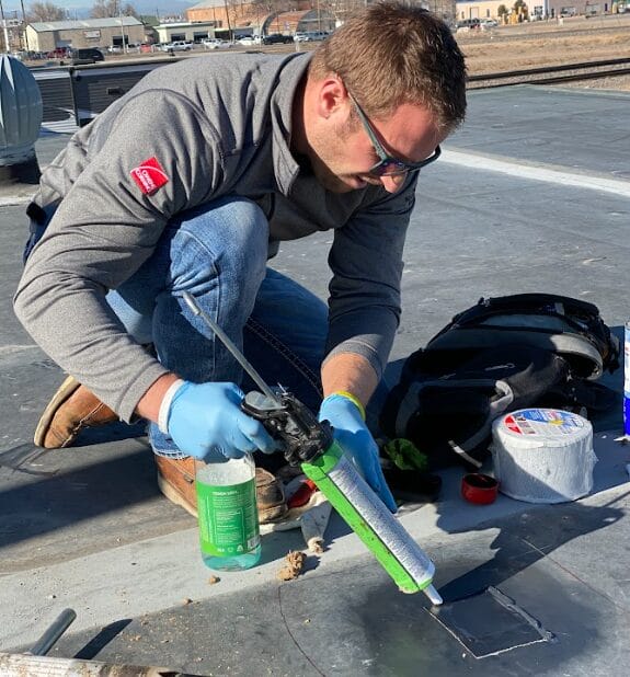 Roofer applying sealant on a commercial flat roof during a repair. 