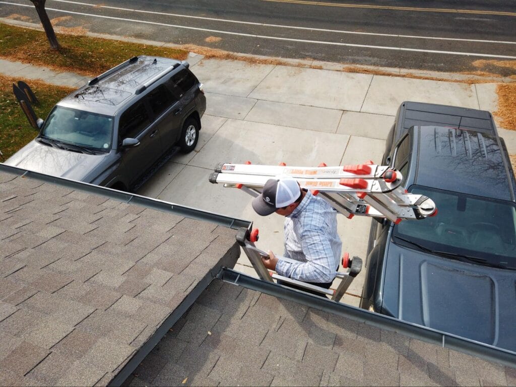 Roofer climbing a ladder to inspect a residential roof.