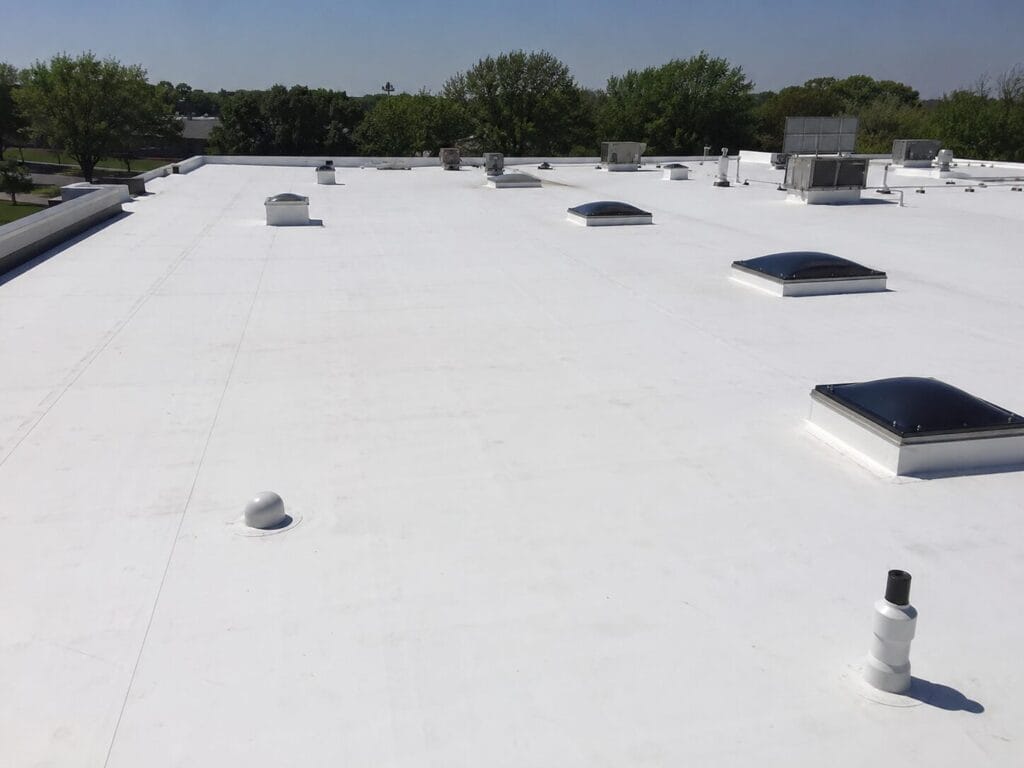 White TPO membrane installed on a commercial flat roof with skylights and rooftop equipment. 
