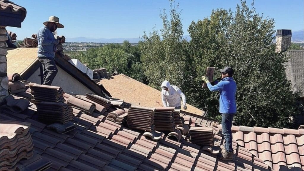 Roofing crew installs concrete roof tiles on a residential home during a roof replacement.