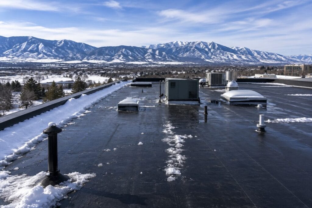 Snow-covered EPDM commercial roof with rooftop equipment.